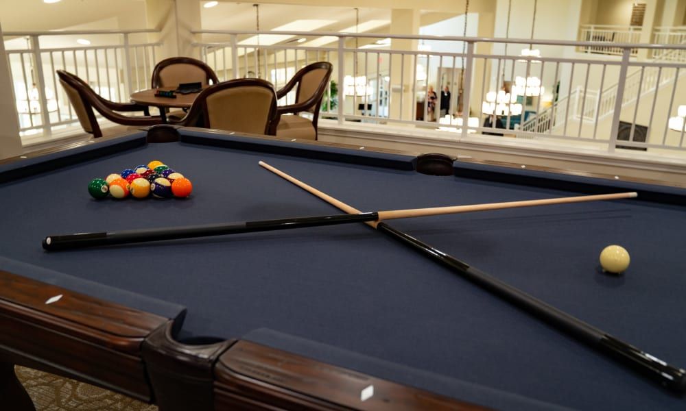 A cozy game room with a pool table set up for play, complete with cue sticks and billiard balls.