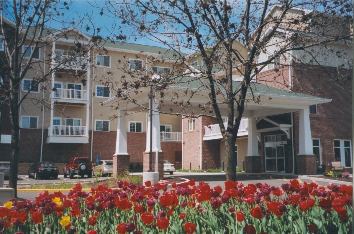 A building entrance surrounded by colorful tulips and trees in a landscaped garden.