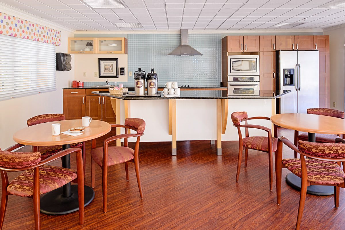 A modern kitchen and dining area with wooden flooring, featuring a coffee station and appliances.