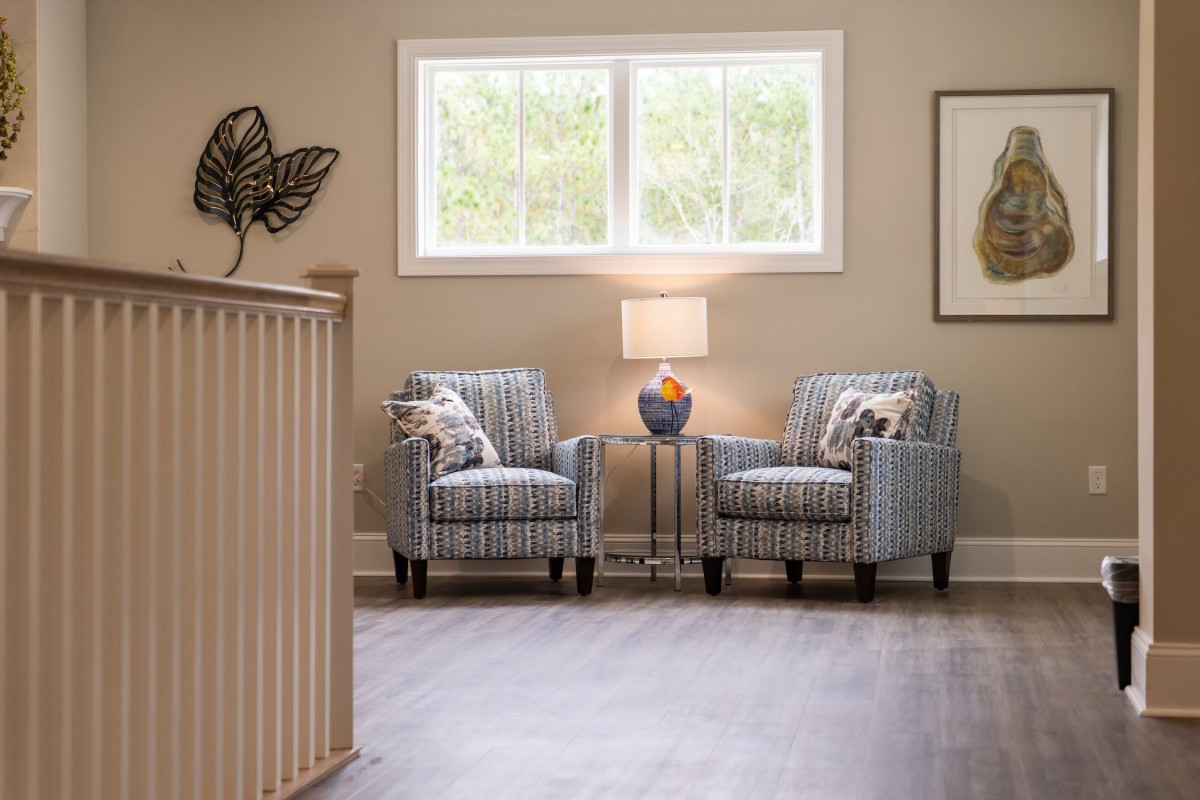 A cozy seating area with two striped armchairs and a table lamp by the window, creating a welcoming atmosphere.