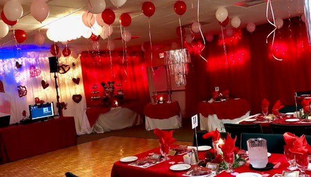 A romantic Valentine's Day themed party with red and white decorations, including heart balloons and elegant table settings.