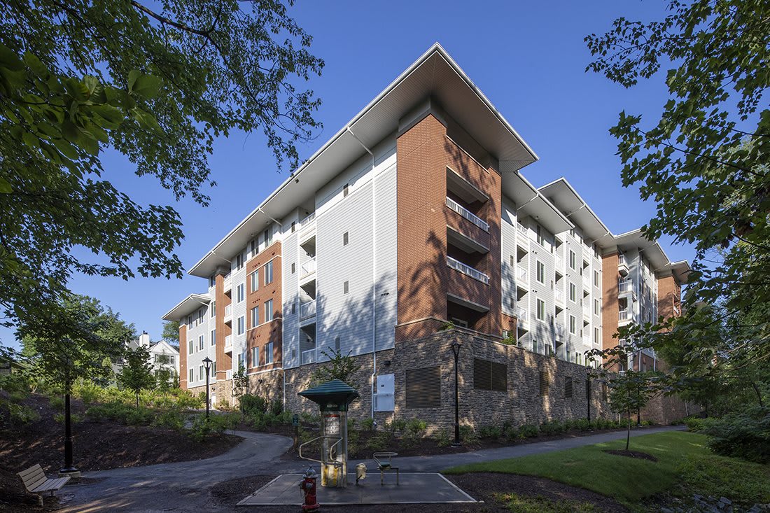 A modern residential apartment building surrounded by trees on a clear day.