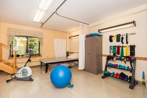 A well-equipped therapy room featuring exercise equipment like a blue exercise ball and weights, ideal for rehabilitation sessions.