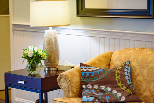 A cozy living room corner featuring a stylish sofa, decorative pillows, a touch of greenery, and ambient lighting.