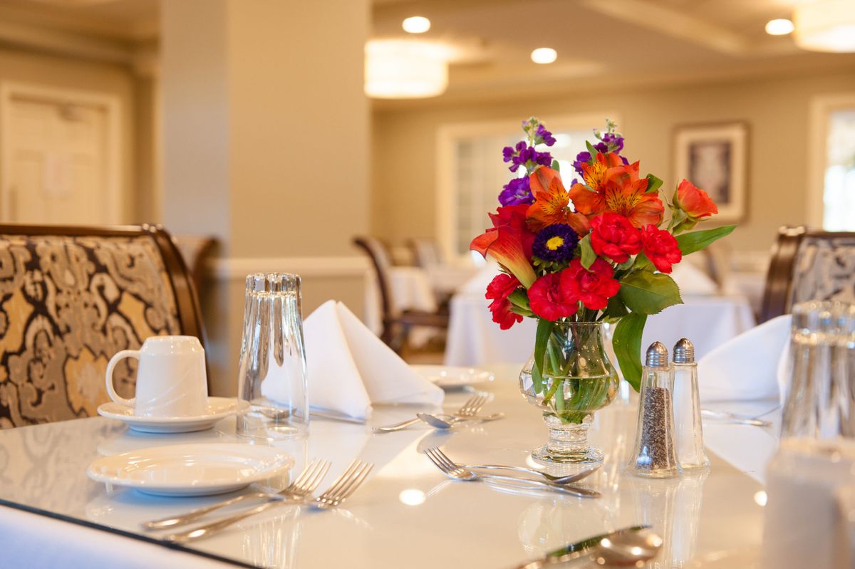 A beautifully set dining table with vibrant flowers in an elegant restaurant setting.