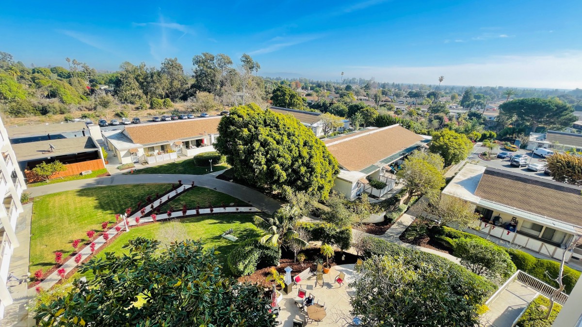 A scenic view of buildings surrounded by lush greenery under a clear blue sky.