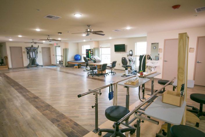 A spacious rehabilitation center equipped with various exercise machines and therapy tools.