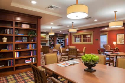 A cozy library interior with bookshelves, tables, and chairs arranged for reading and study.
