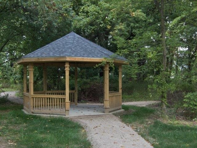 A wooden gazebo surrounded by trees with a pathway leading to it.