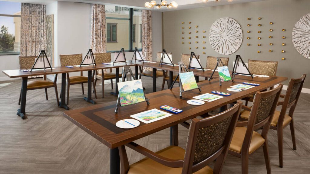 A well-organized art studio set up for a painting class, featuring easels and art supplies on tables.