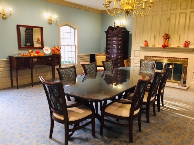 A classic dining room with a polished table, elegant chairs, and a chandelier overhead.