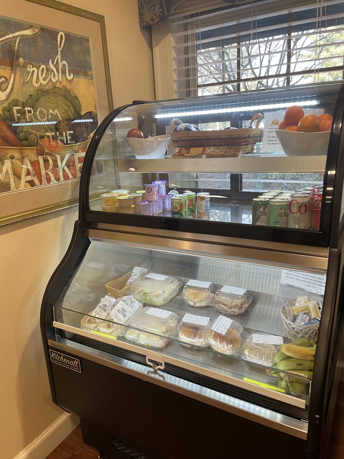 A display case filled with a variety of sandwiches and deli items inside a market.