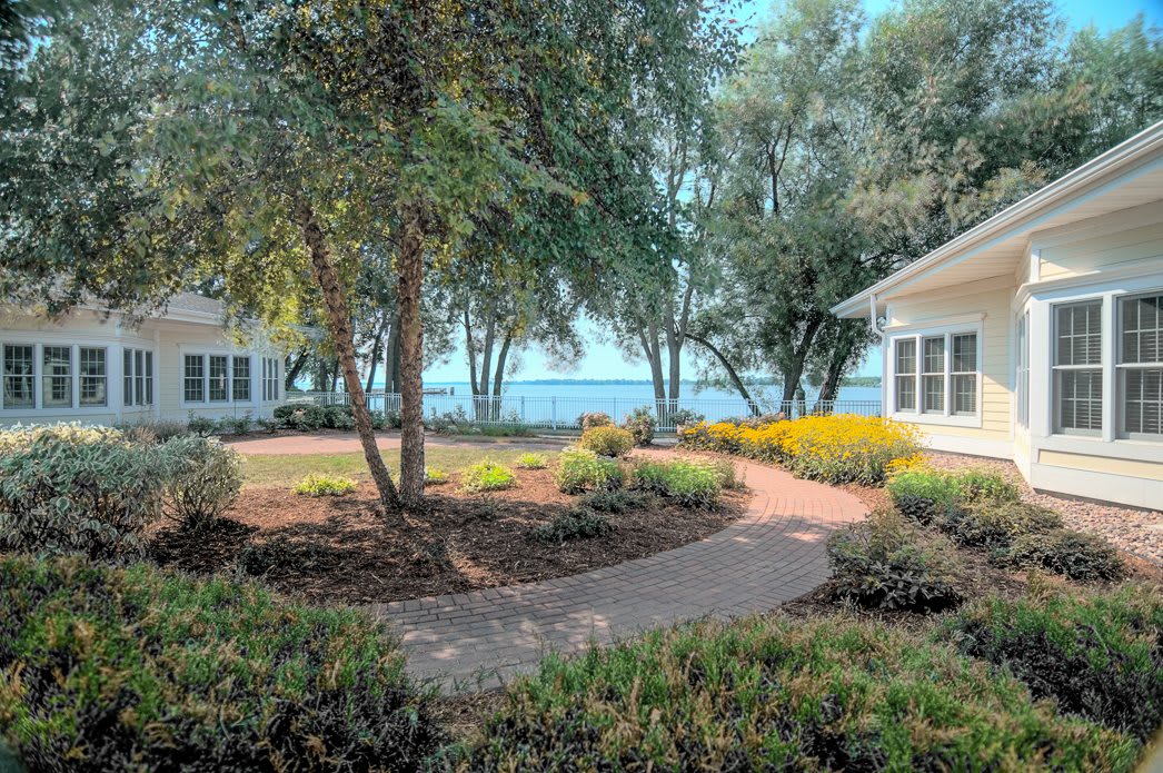 A scenic garden pathway leading to a view of the lake, surrounded by lush trees and greenery.
