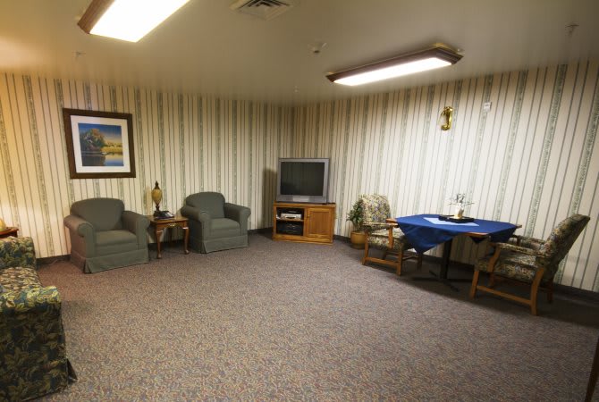 A cozy living room with armchairs, a television, and a small table.