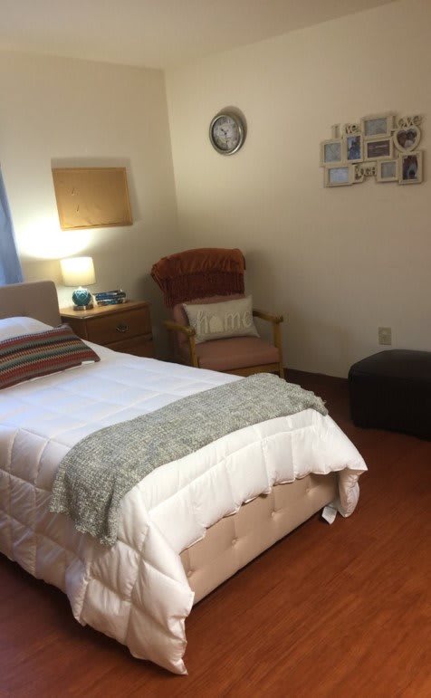 A cozy bedroom with a neatly made bed, armchair, and warm lighting.