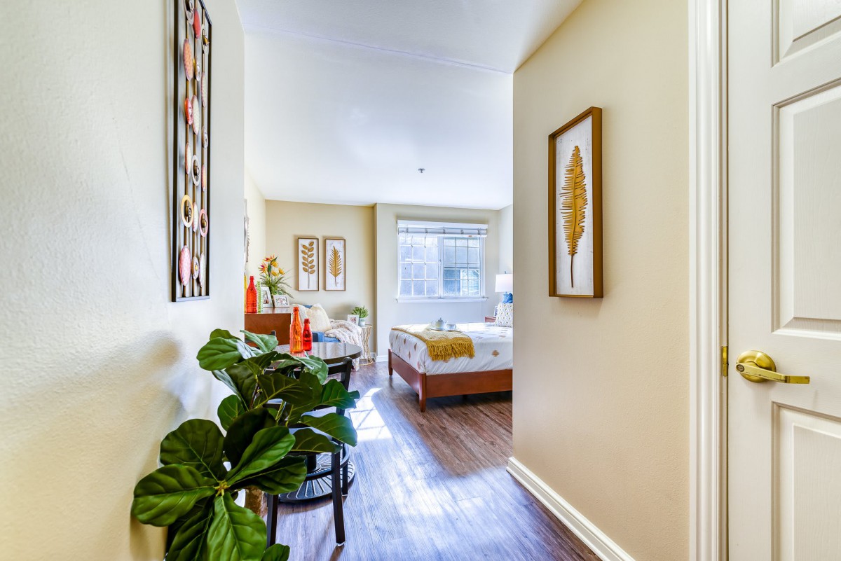 A bright and inviting apartment hallway leading to a cozy bedroom with tasteful decor.