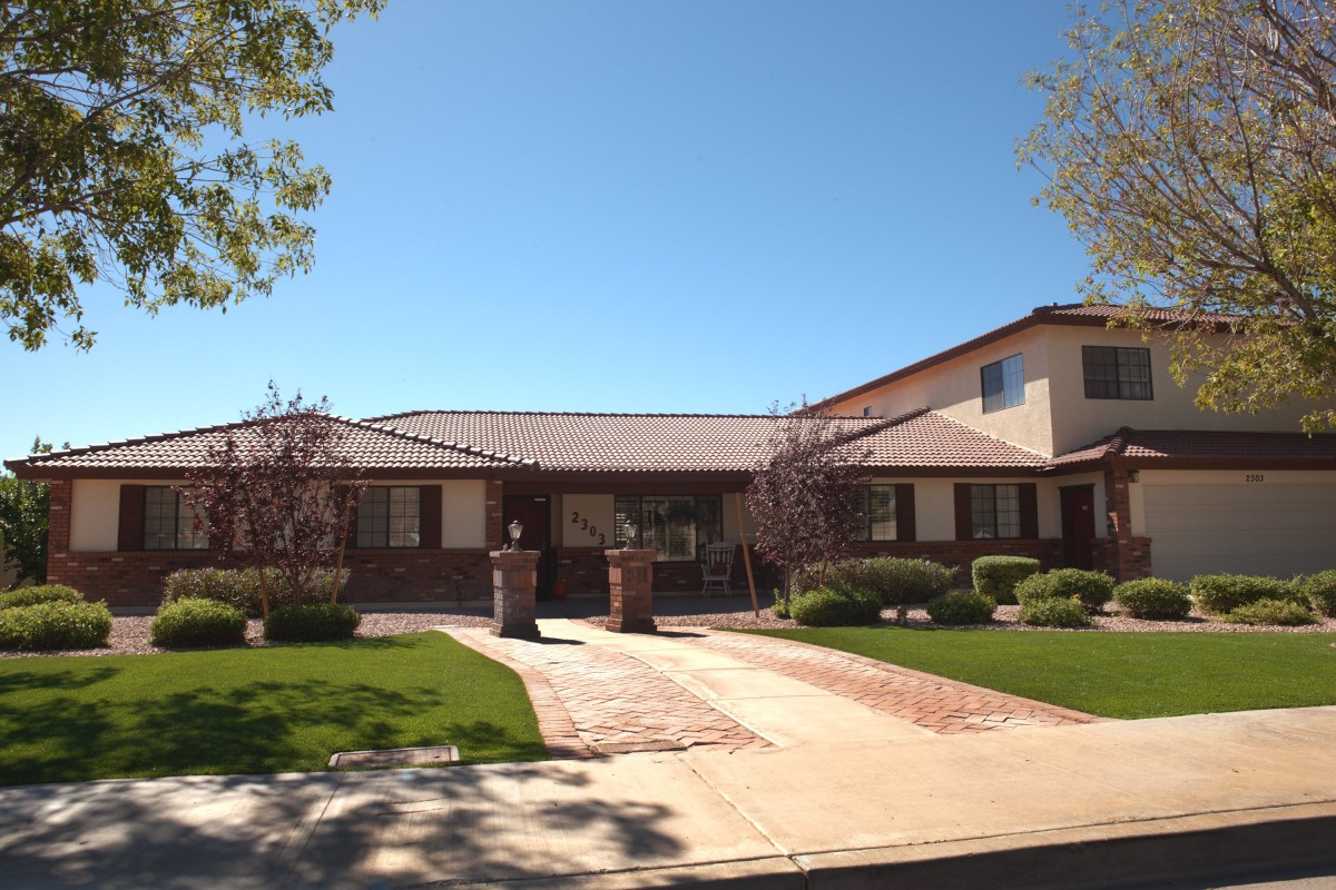 A suburban house with a well-maintained lawn and a driveway on a sunny day.
