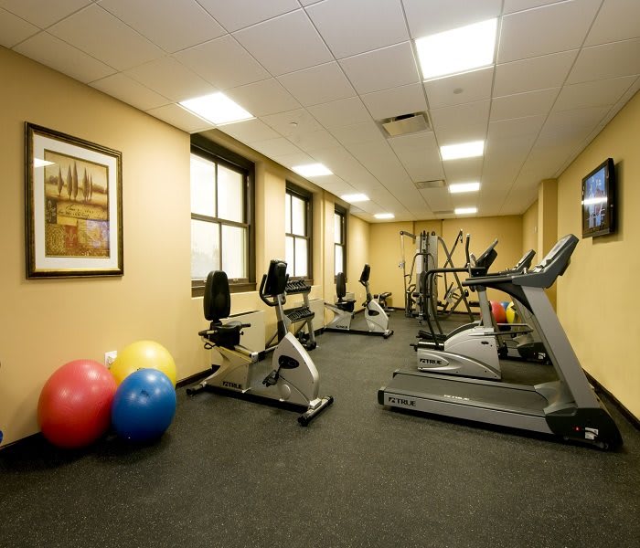 A small indoor gym with exercise equipment including treadmills, stationary bikes, and fitness balls.