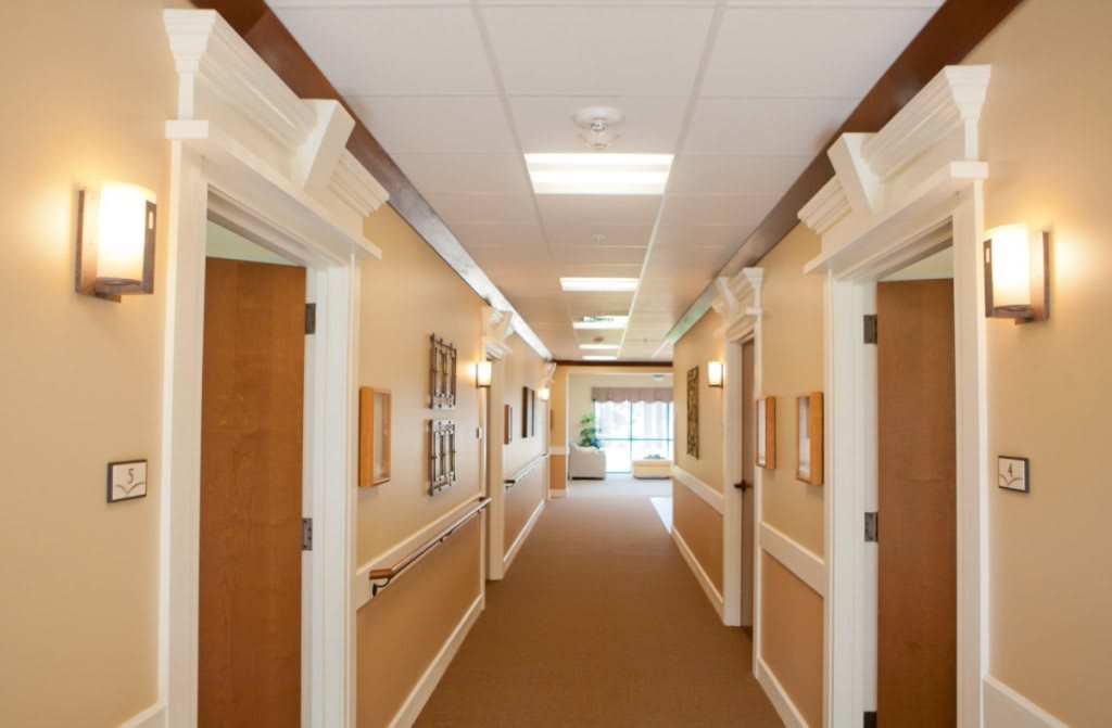 A well-lit hallway with multiple doors and framed pictures on the walls.