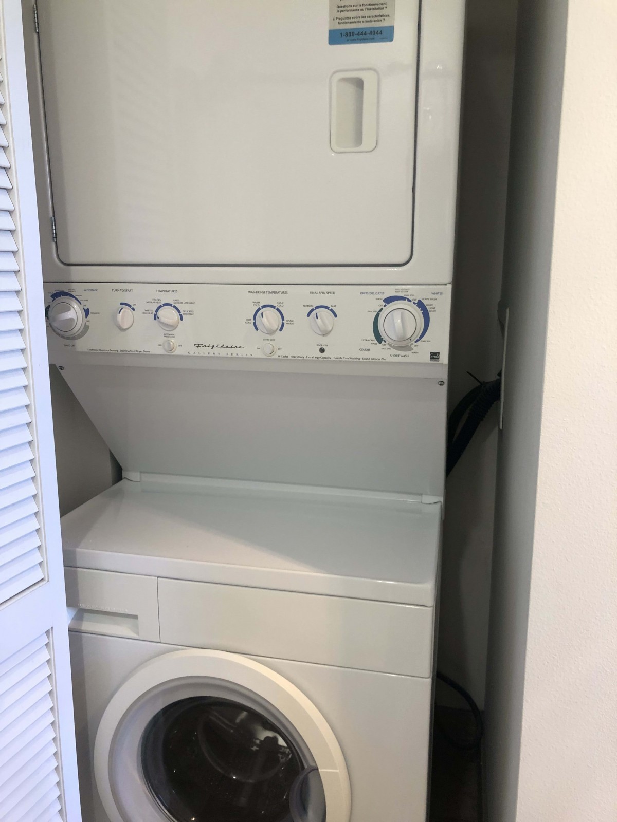 A compact stacked washer and dryer unit in a small closet.