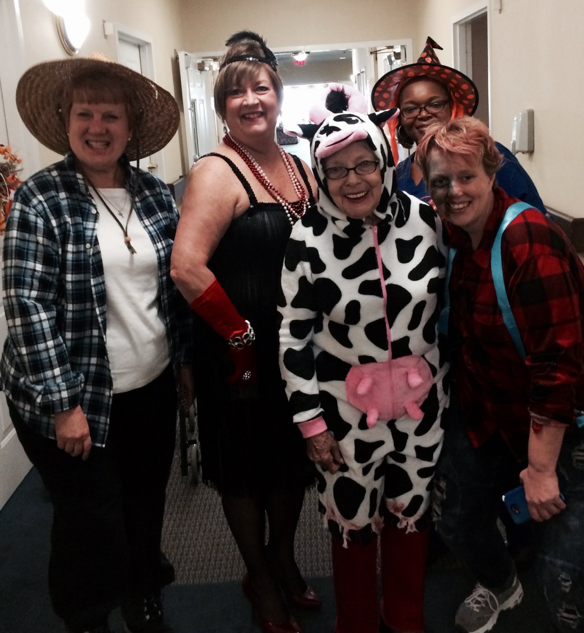 A group of people dressed in various costumes, including a cow suit and themed hats.