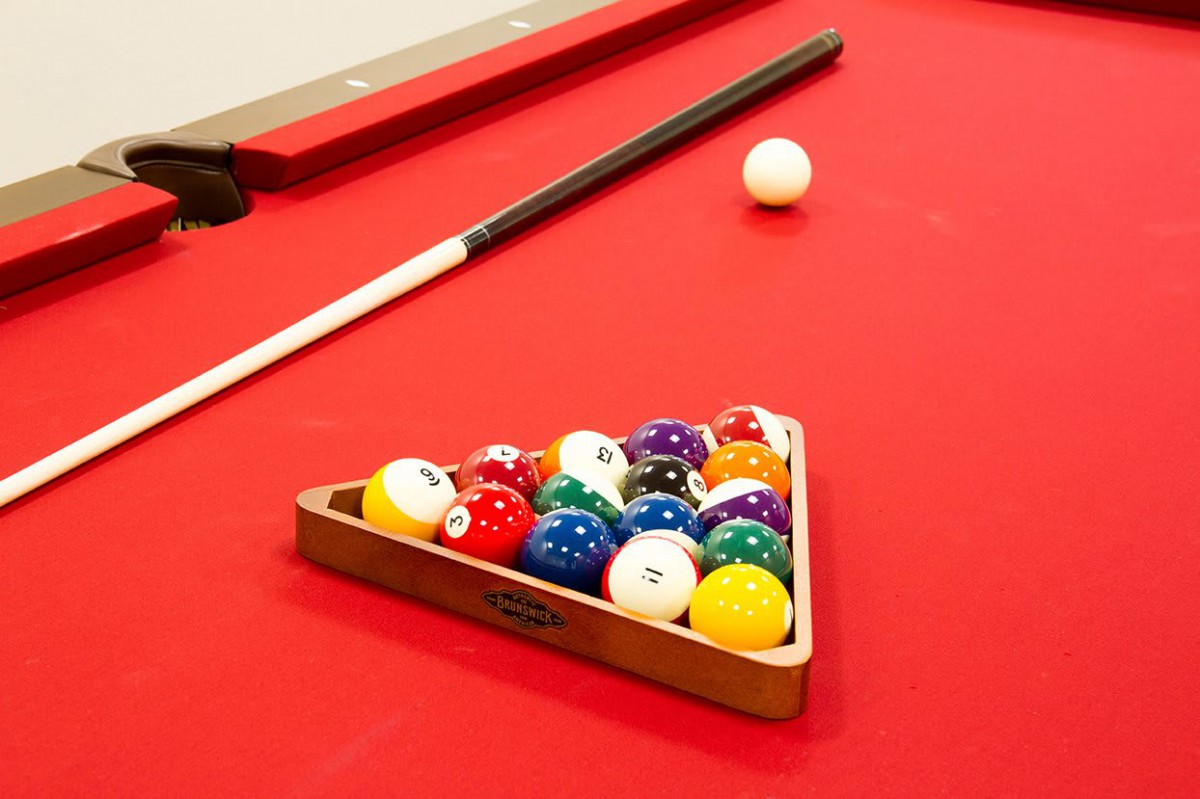 A pool table with a set of billiard balls arranged in a triangle, ready for a game.