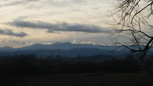 A serene view of the mountains under a cloudy sky during dusk.