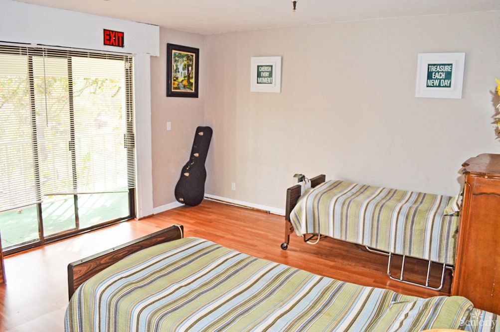 A minimalist bedroom with two beds and a guitar case by the window.