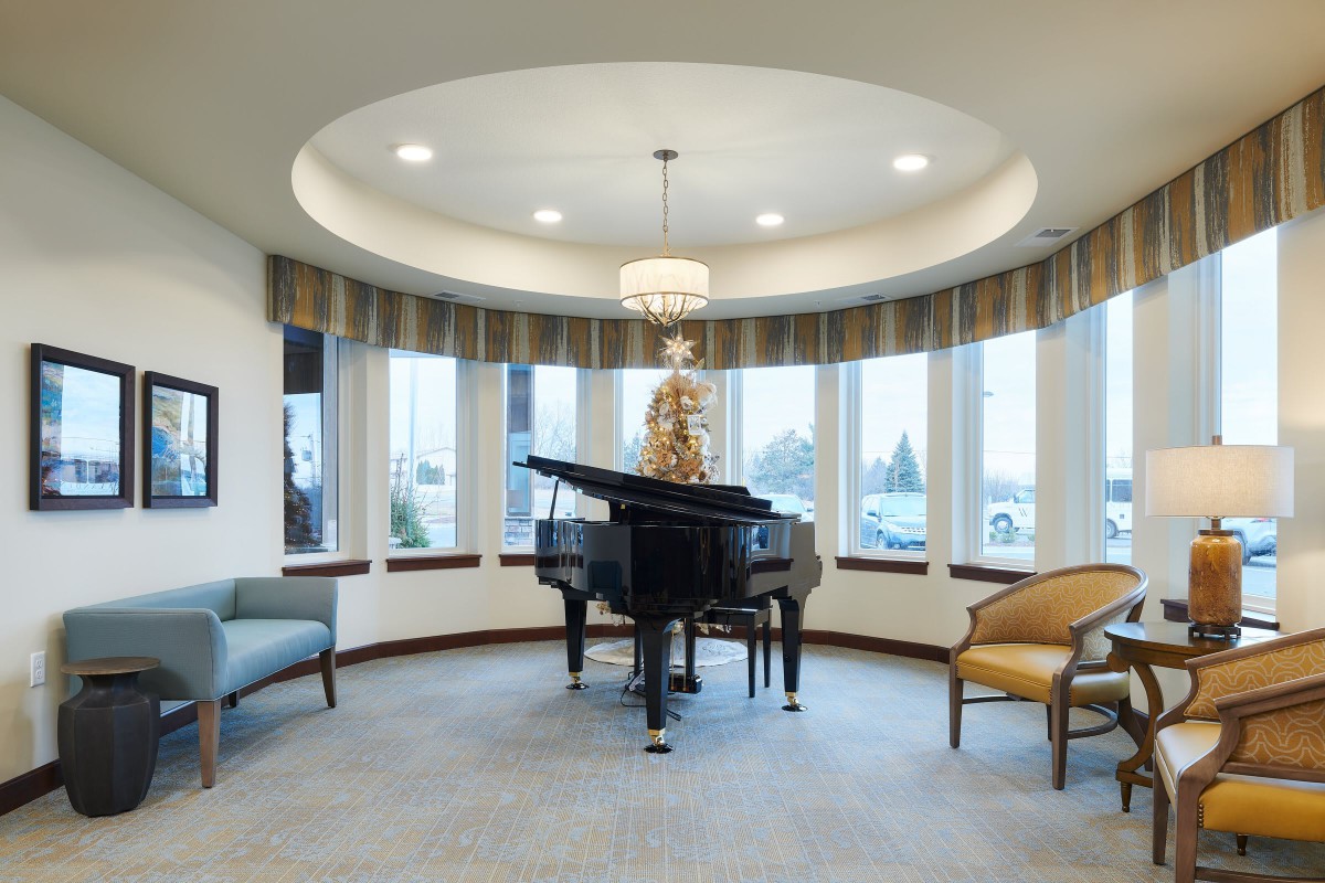 A luxurious living room featuring a grand piano surrounded by elegant seating and a chandelier.
