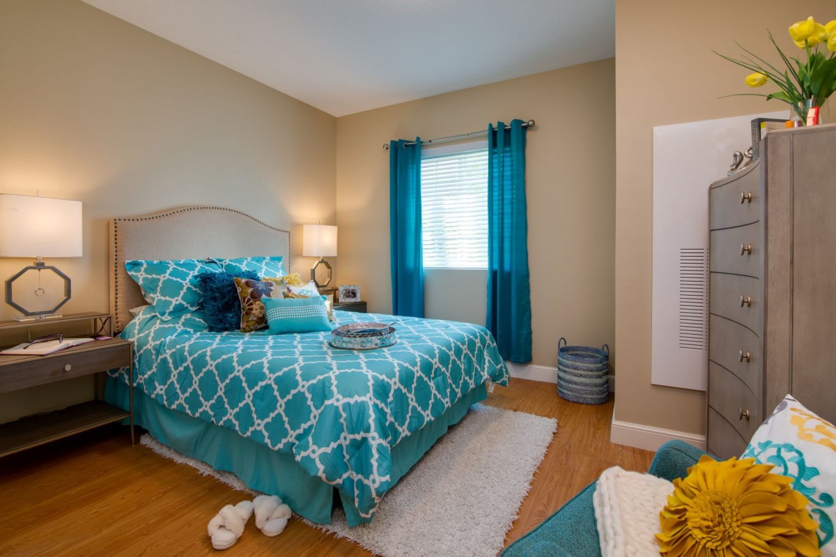 A cozy bedroom featuring blue accents and a neatly made bed.