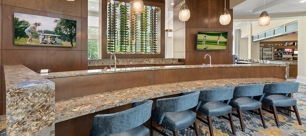 A modern bar area featuring a granite countertop, stylish seating, and a wine rack display.