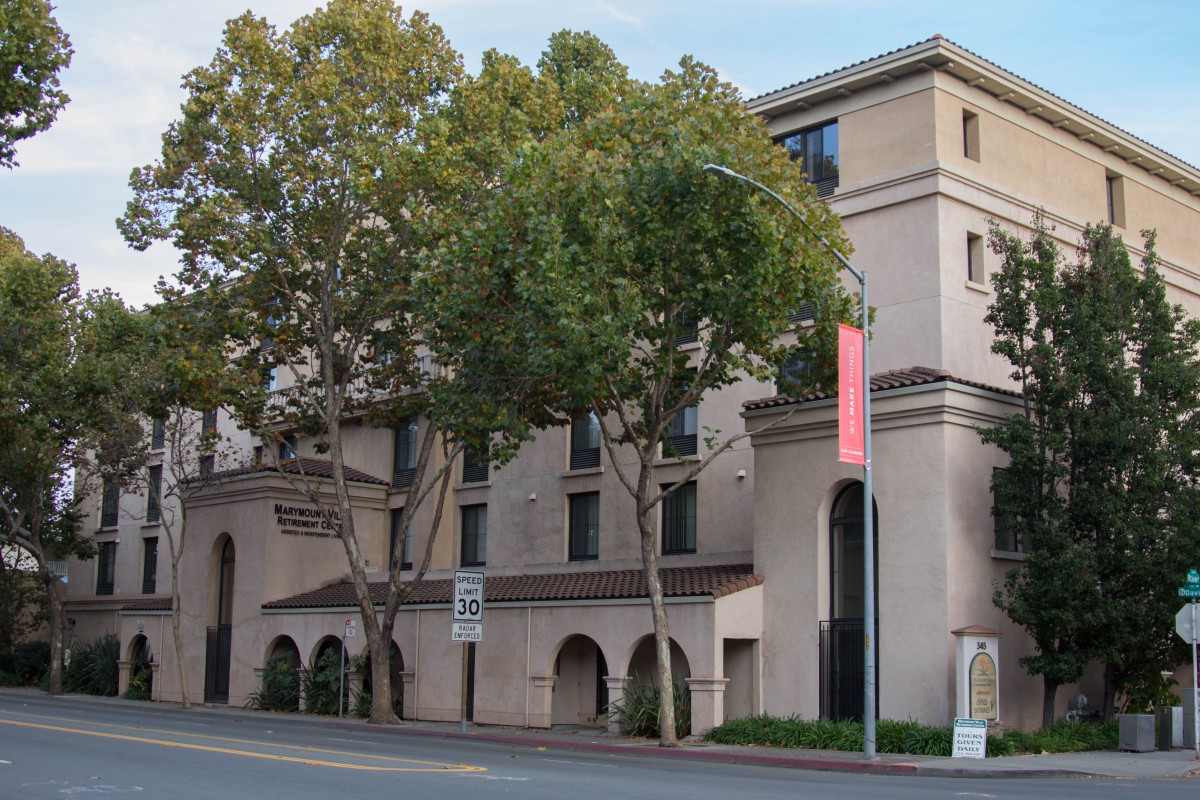 A street view of a multi-story building with trees in front.