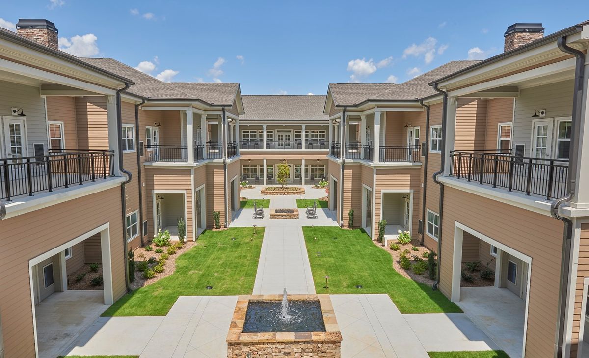 A modern apartment complex with a landscaped courtyard and central fountain.