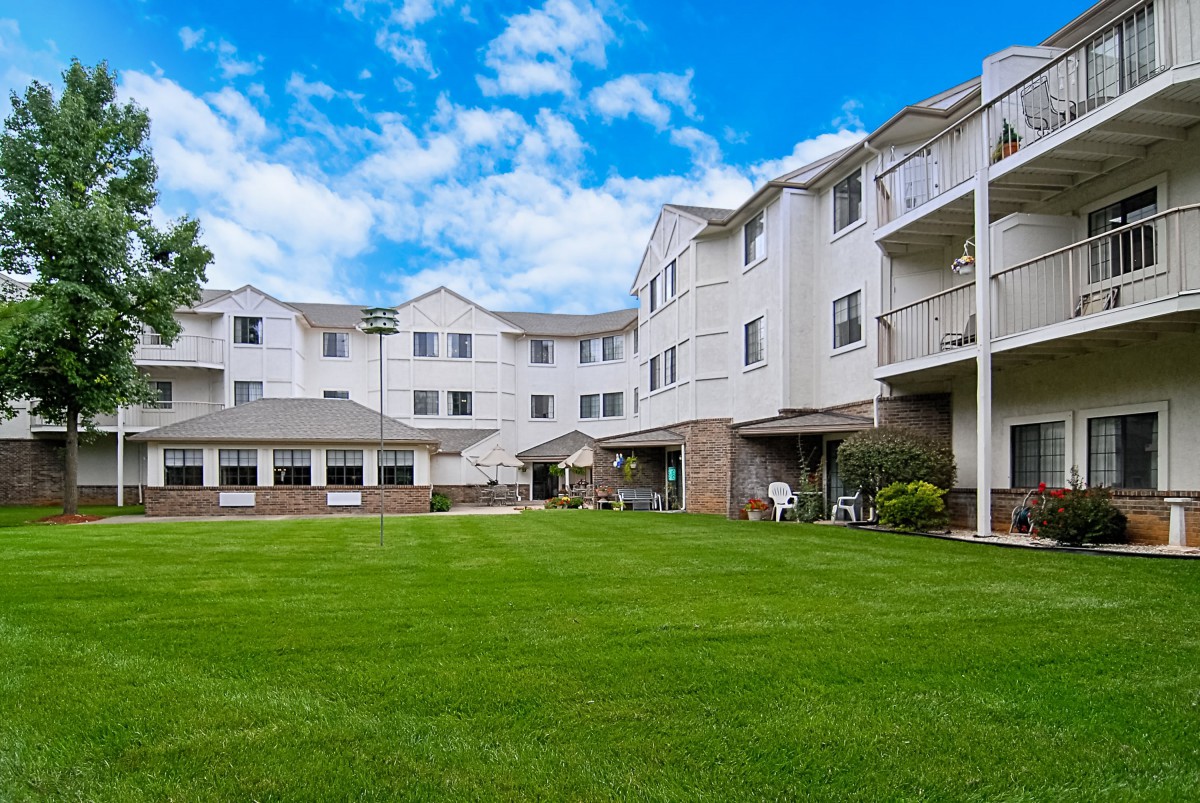 A residential apartment complex with a spacious green lawn under a clear blue sky.