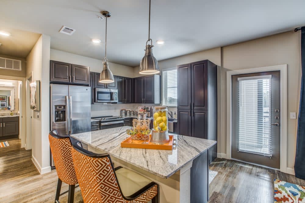A modern kitchen with a marble island, pendant lighting, and contemporary appliances.