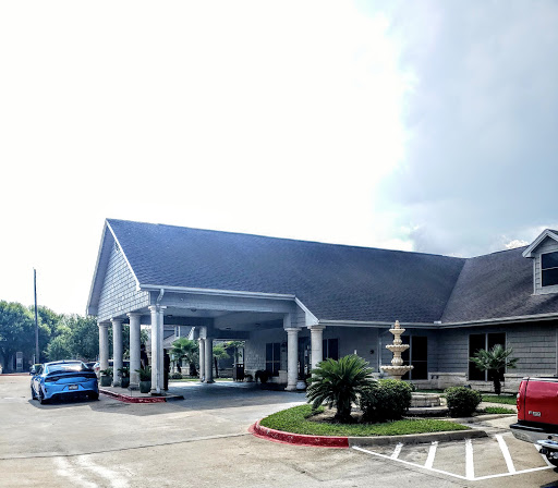 A welcoming entrance to a well-maintained building, featuring a landscaped area and a parked car.