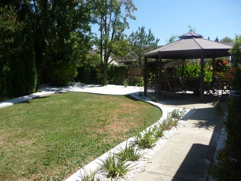 A tranquil backyard with a gazebo overlooking a spacious lawn and surrounding trees.
