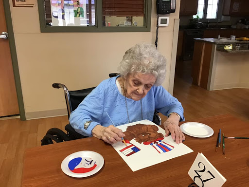 An elderly woman engaged in a creative painting activity, showcasing her artistic skills.
