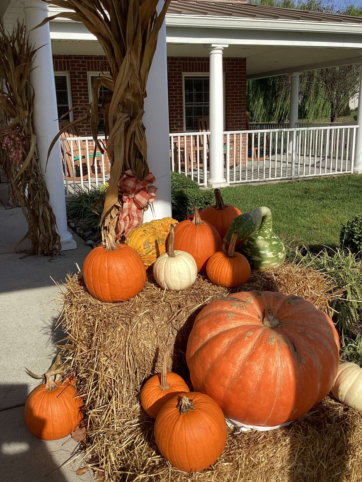 A seasonal display of pumpkins and hay bales on a porch, celebrating the autumn season.