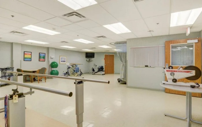 A well-equipped physical therapy room with exercise machines and parallel bars.