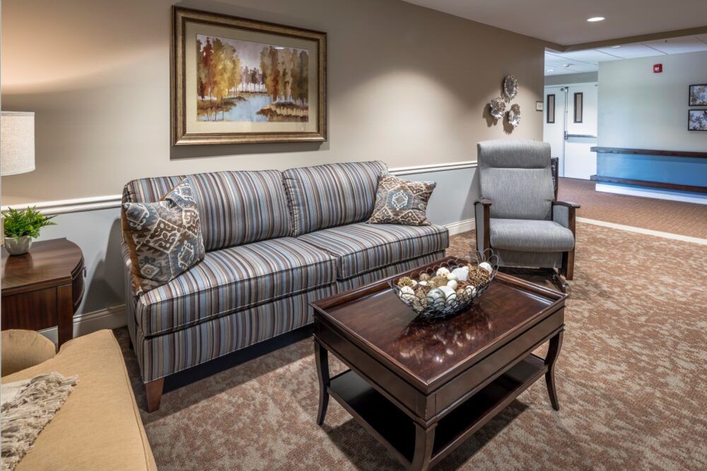 A cozy living room setting featuring a striped sofa, a comfortable armchair, and a wooden coffee table adorned with decorative items.