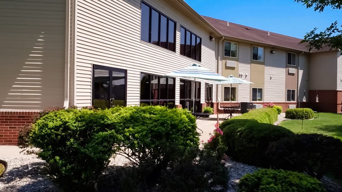 A sunny view of a modern building with large windows and well-maintained landscaping.