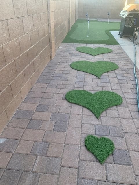 A decorative stone pathway with heart-shaped patches of artificial grass.