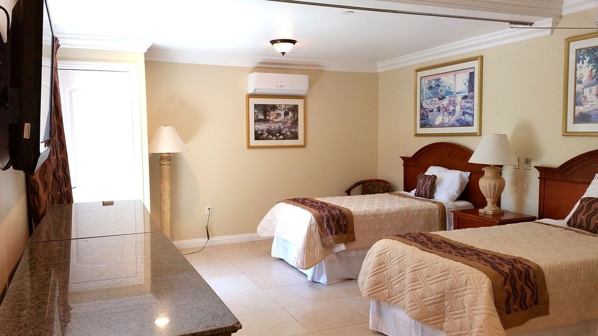 A well-lit hotel room with two neatly made single beds and decorative wall art.