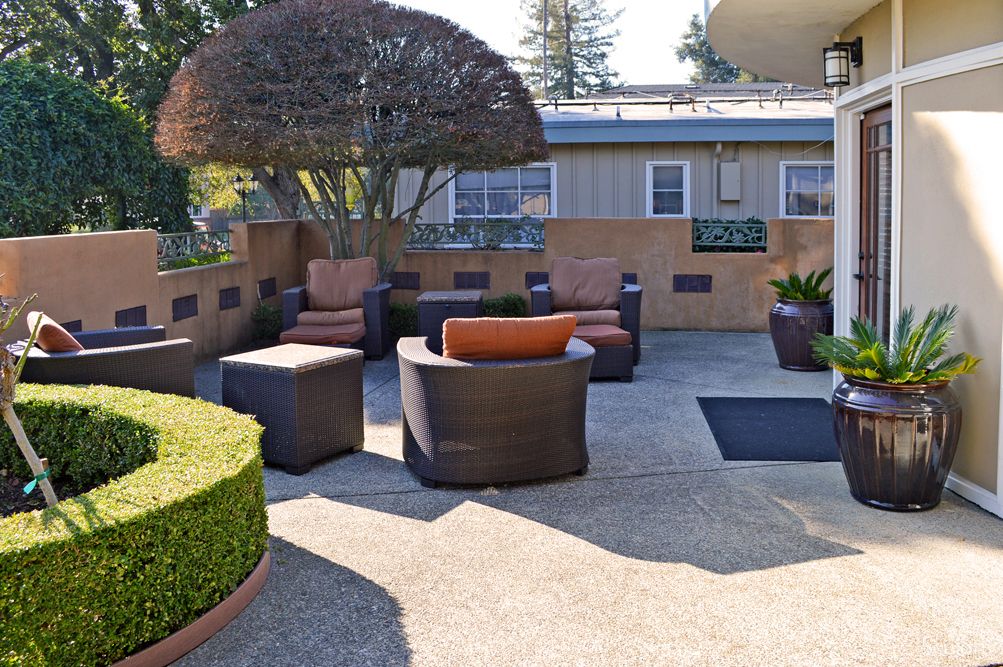 A cozy outdoor patio with comfortable seating surrounded by lush landscaping.