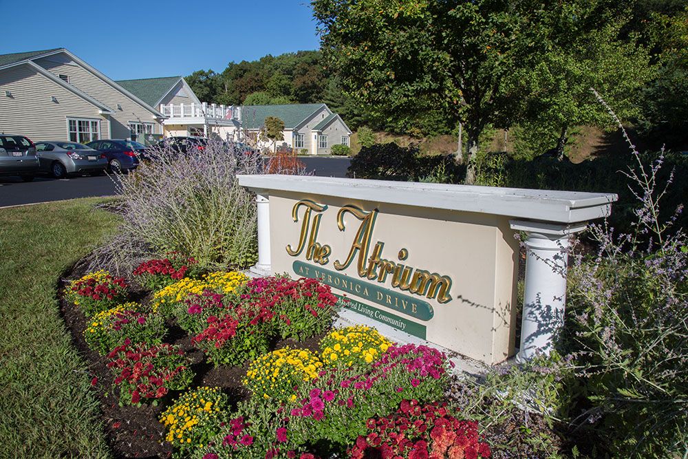 A landscaped garden with colorful flowers surrounds a sign reading 'The Atrium' near a building.