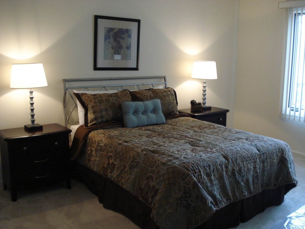 A cozy bedroom with a neatly made bed flanked by two nightstands and lamps.