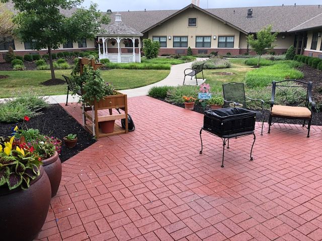 A peaceful garden with a brick patio, outdoor furniture, and a gazebo in the background.
