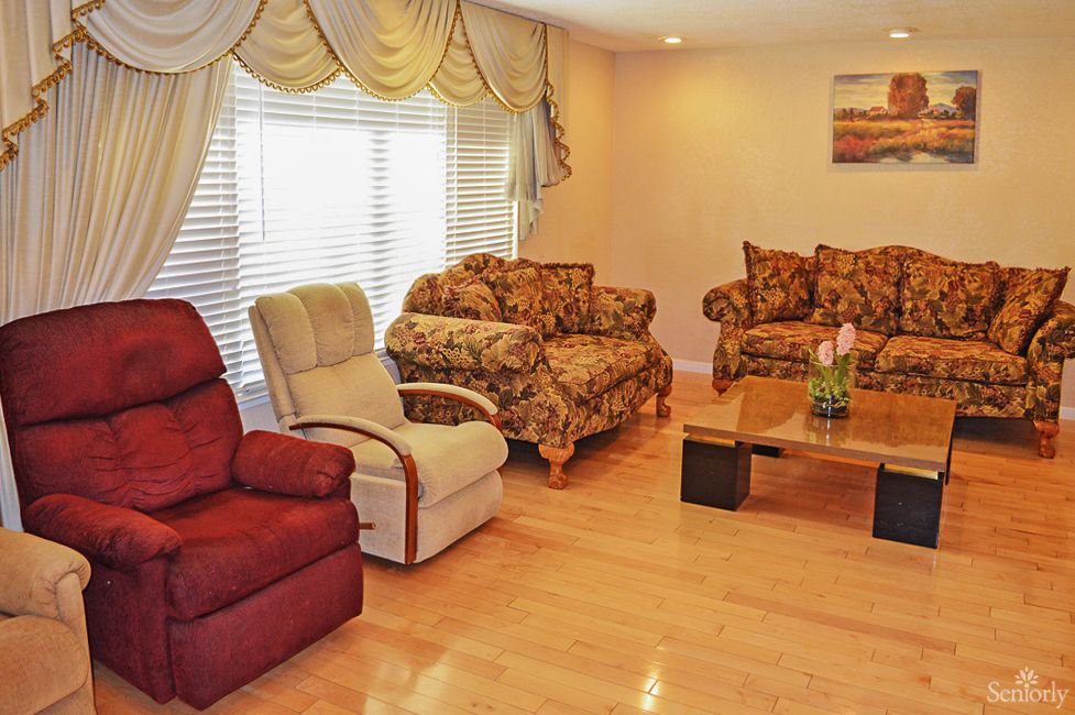 A cozy living room with patterned sofas, armchairs, and a wooden coffee table.