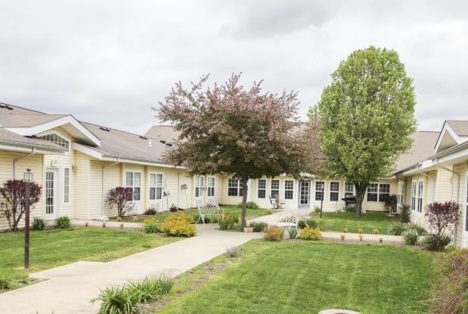 A single-story house surrounded by a well-maintained lawn and garden with trees.